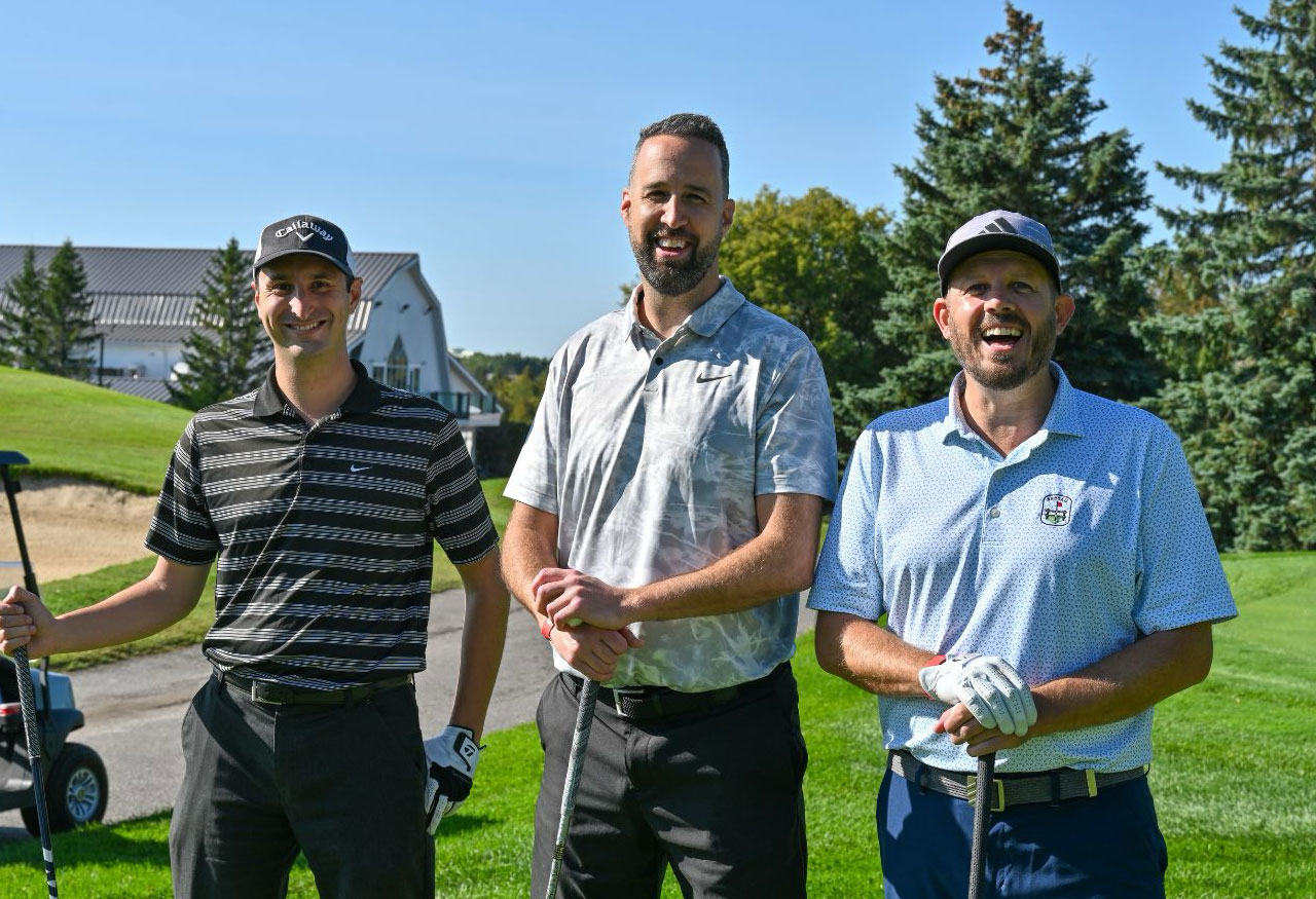 Three men golfing at a tournament smiling